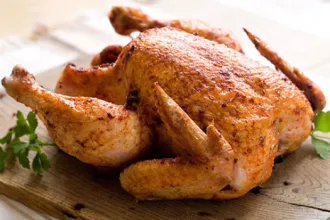 Whole oven roasted chicken on a board.