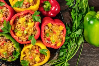 PICT RECIPE Peppers Stuffed with Rice and Beans - USDA Serving dish of peppers stuffed with rice and beans next to a whole green bell pepper and bundle of cilantro.