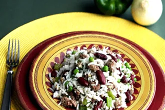 Overhead view of a bowl of dirty rice resting on a plate. A fork is next to the plate.